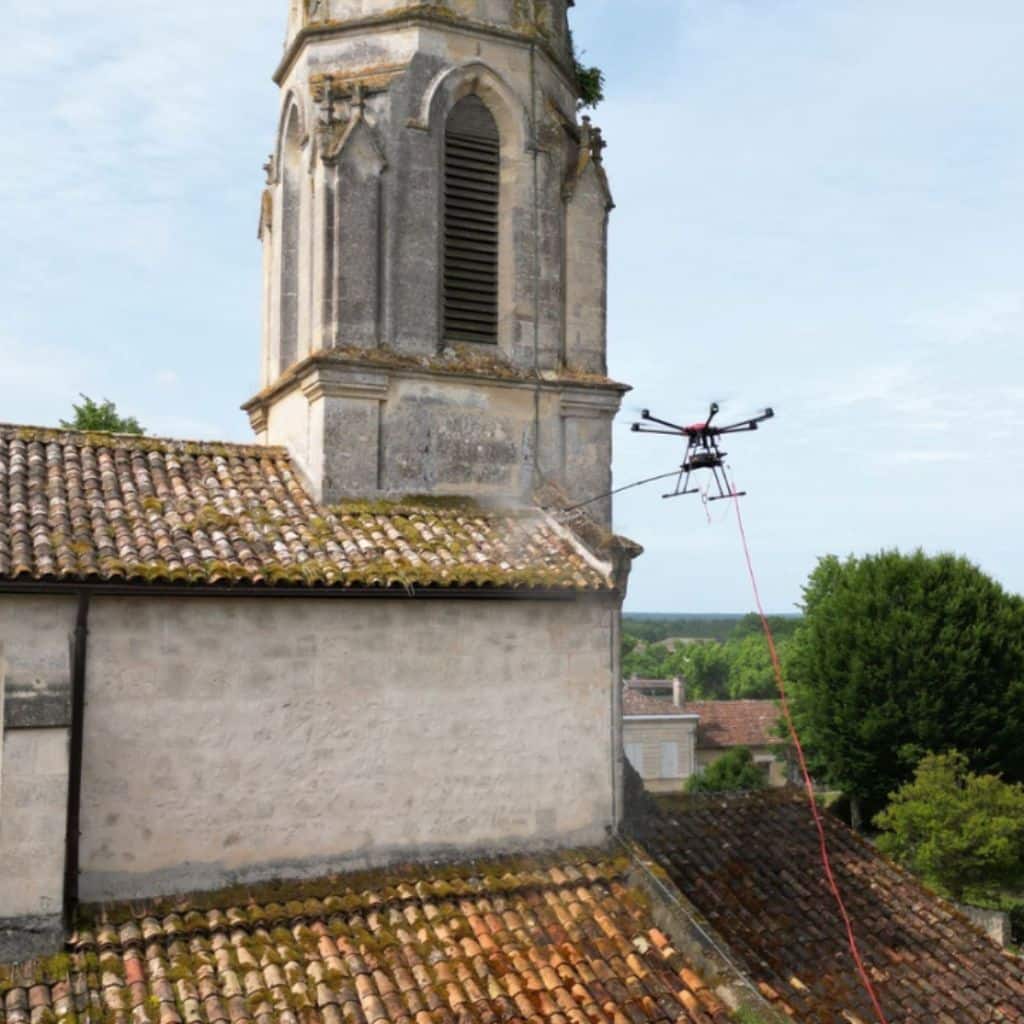 Drone professionnel en train de traiter la toiture d'un monument historique avec précision.