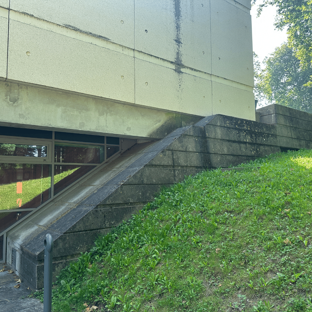 Pan du bâtiment du Mess à Bayonne avant nettoyage : coulures noires de ruissellement sur la façade et soubassements en béton fortement encrassés.